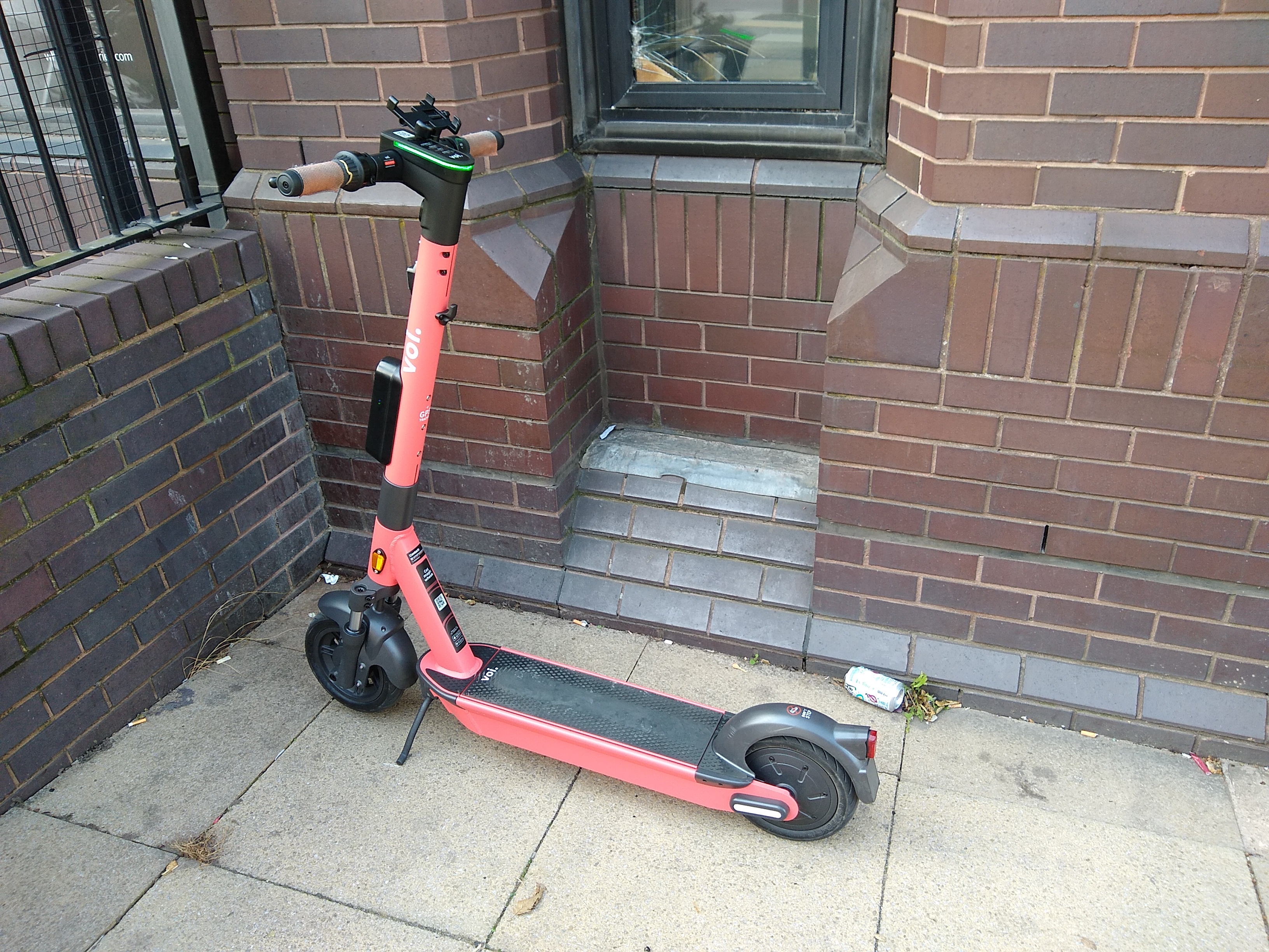 Voi electric hire scooter parked against a wall